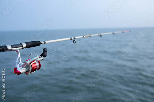 fishing rod and spinning reel and sea water background
