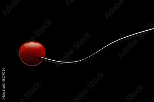Cherry tomato on a fork with black background