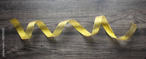 Golden ribbon on dark wooden background