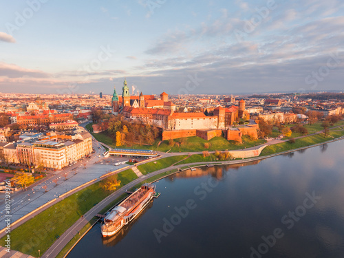 Drone aerial view at gold sunset time of royal Castle in Cracow city center, Vistula river. Krakow, Poland