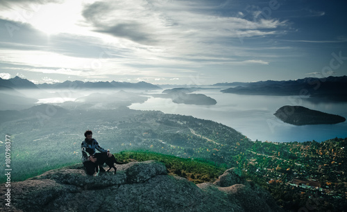 Man with dog at the top of the mountain with lake view