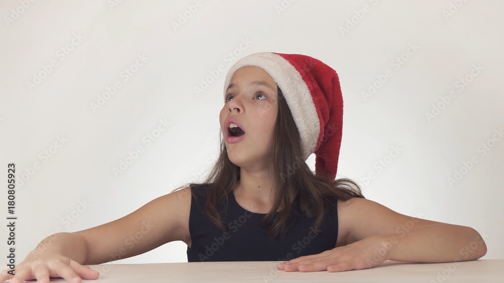 Φωτογραφία Beautiful happy girl teenager in a Santa Claus hat look and emotionally expresse