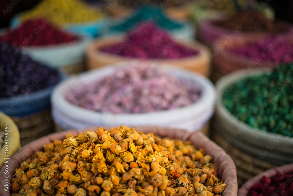 Piles of colourful, vibrant herbs and potpourri in a market stall in a souk in Marrakech, Morocco