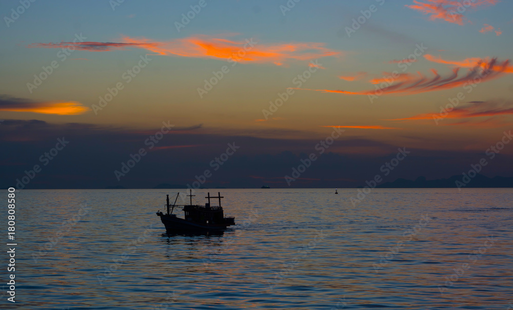 SILHOUETTE FISHERMAN BOAT , WONDERFUL EVENING TIME SCENIC DRAMATIC SKY TWILIGHT CLOUD ABOVE ISLAND IN BACKGROUND, LIGHT REFLECTING ON WATER