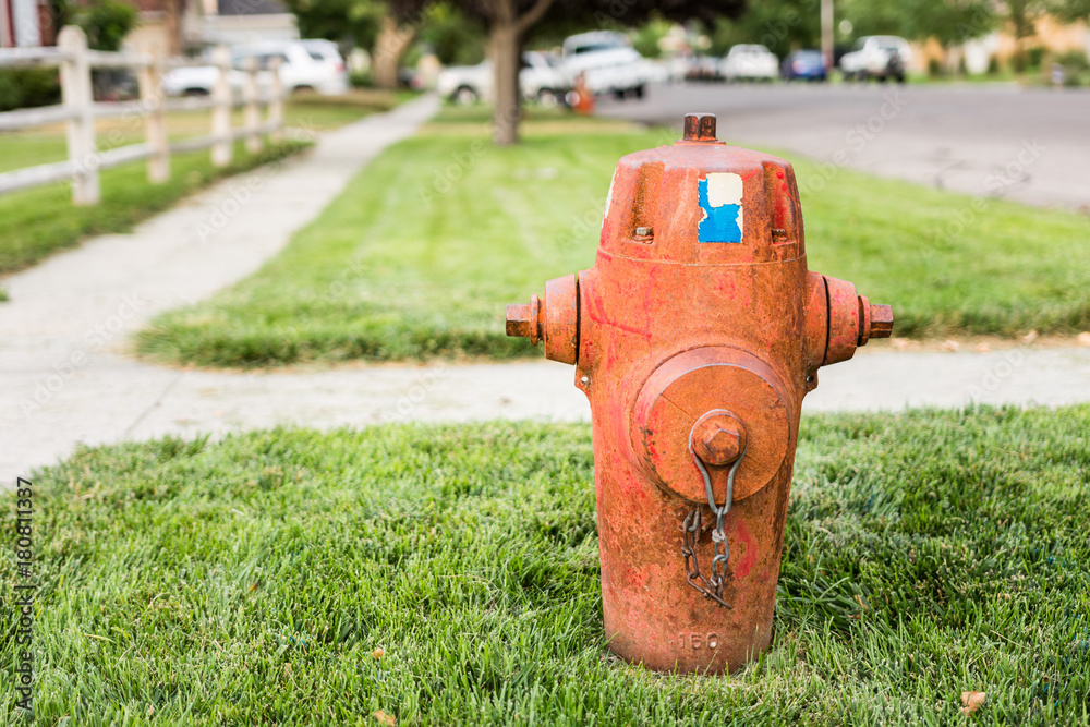 Dirty old fire hydrant on grassy street corner of urban community