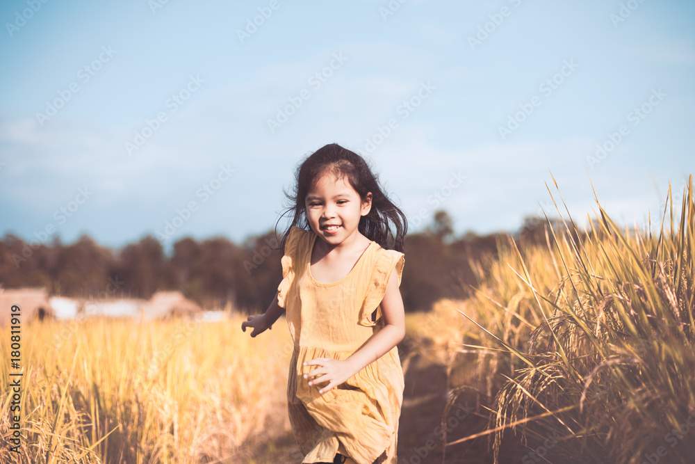 Cute asian child girl having fun to run in the cornfield in vintage color tone