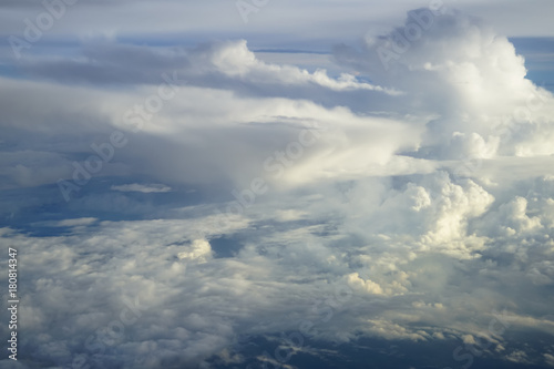 View of abstract soft free form wind blow white cloud  with shades of blue sky background from above flying plane window in morning sunrise