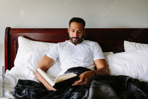 African man reading a book in bed