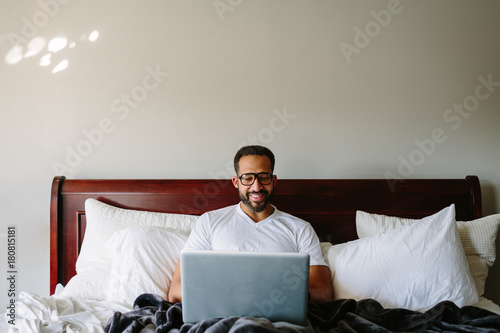 Black man working in bed with laptop computer