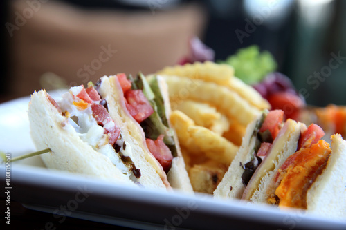 Club sandwich with chicken breast , bacon , tomato , cucumber and fried potatoes