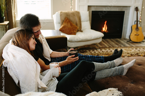 Couple sitting on the couch cuddling and drinking hot chocolate