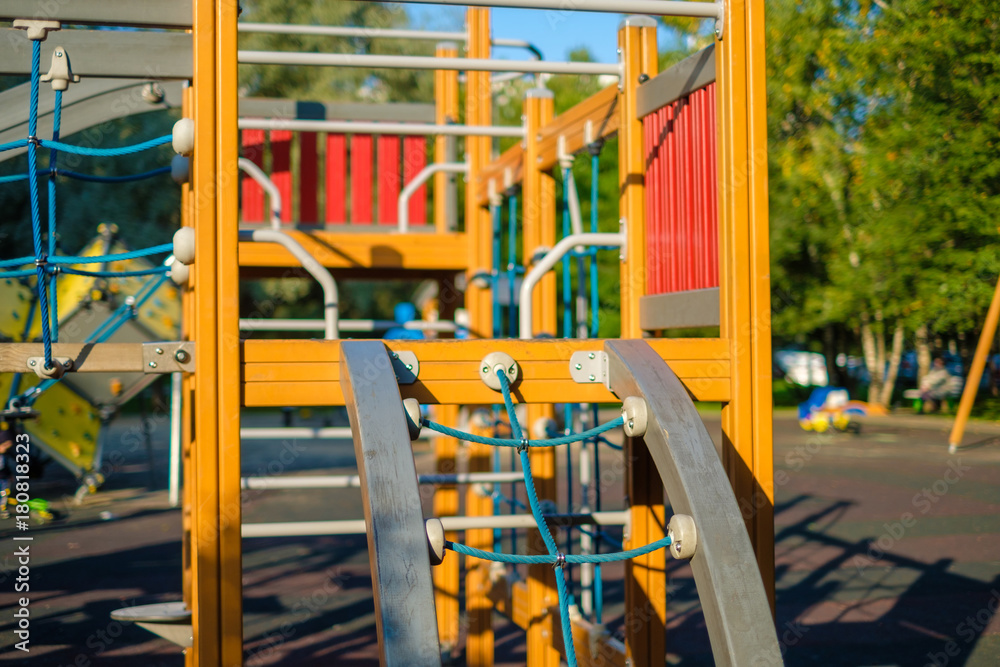 Modern equipped kids playground in sunny day. Rope bridge with net and crawl construction