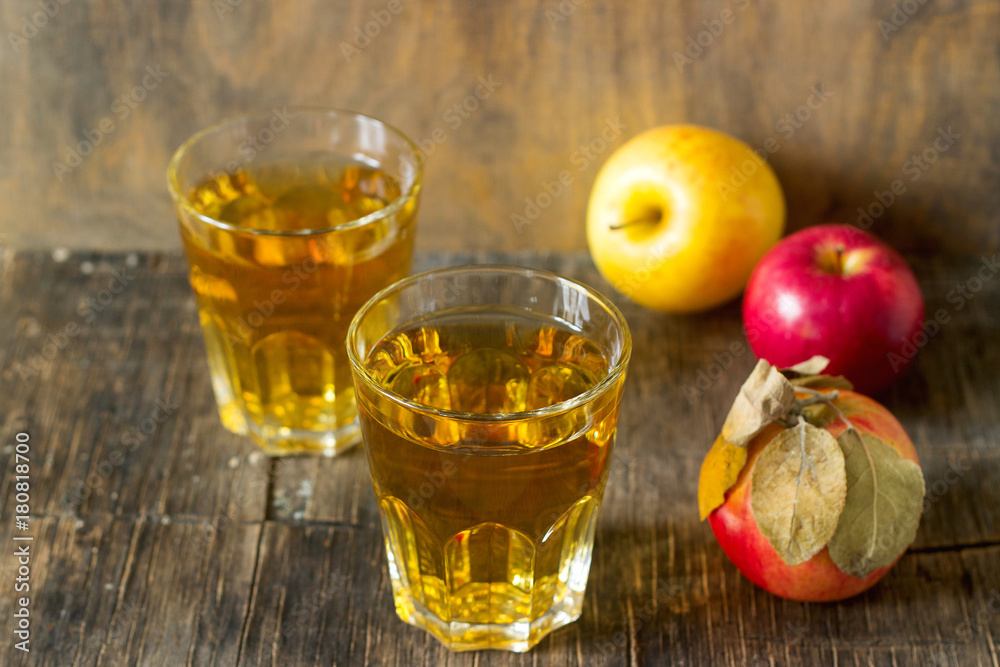 Apple juice in glasses and fresh apples on a wooden background. Rustic style. Apple juice in glasses and fresh apples on a wooden background. Rustic style.
