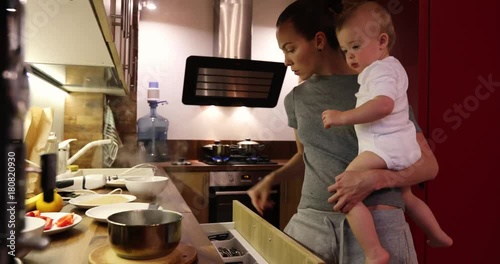 The mother and the baby are trying the prepared food and giving it to the baby.Mom with her baby boy while cooking in the kitchen