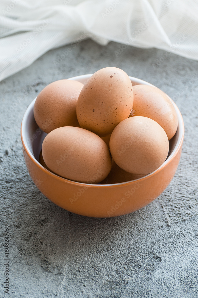 Brown chicken eggs in a bowl on a gray stone table.. Brown chicken eggs in a bowl on a gray stone table..