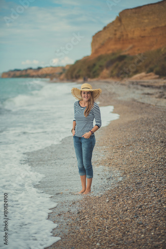 Adorable beauty lady woman eve walking posing alone on beach sea side ocean vacation wearing modish blue jeans shirt and huge hat with touchy landscape of sand cliff cape