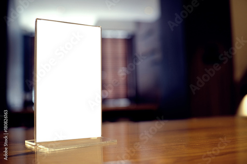 Mock up Menu frame standing on wood table in Bar restaurant cafe. space for text.