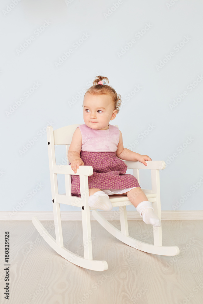 beautiful little girl in a dress sits on a white chair beautiful little girl in a dress sits on a white chair