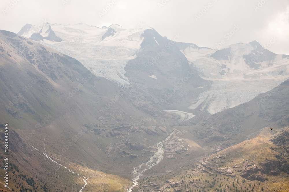 Fototapeta premium montagna innevata con fiume e alberi verdi
