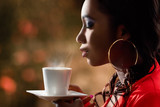 Attractive African woman smelling hot cup of coffee.