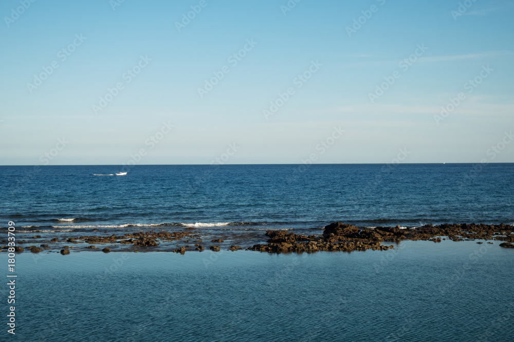 Atlantic ocean with rocks and boat behind 
