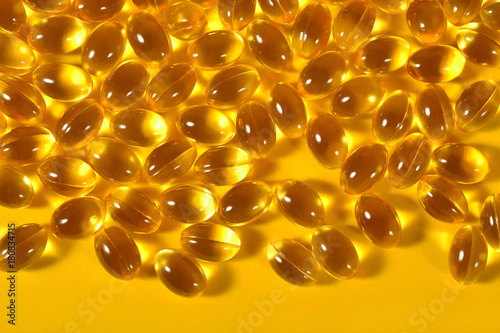 Omega-3 fish fat oil capsules on a yellow background