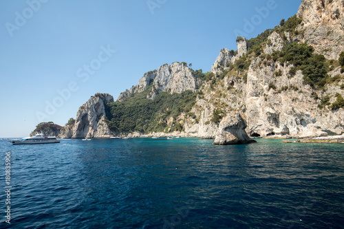 View from the boat on the Boats with tourists and the cliff coast of Capri Island. Italy