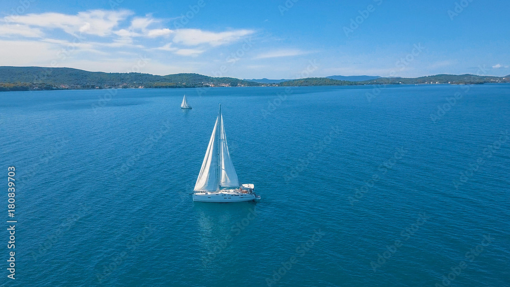 Fototapeta premium Aerial view of yacht sailing near beautiful Islands. Beautiful clouds in the background. Luxury yacht in the sea.