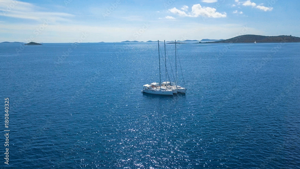 Fototapeta premium Aerial view of yacht sailing near beautiful Islands. Beautiful clouds in the background. Luxury yacht in the sea.