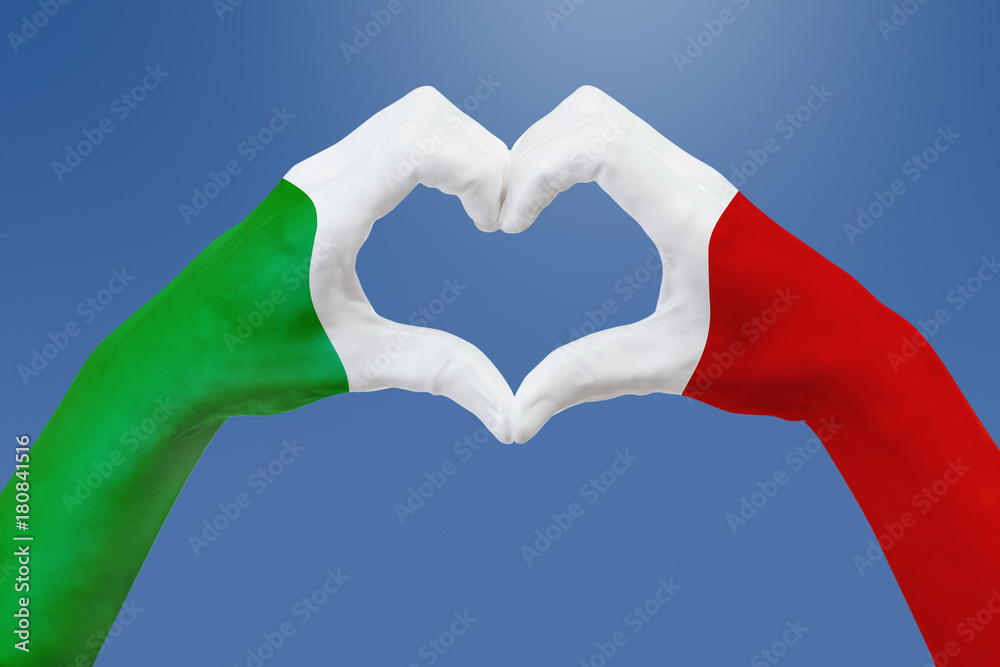 Obraz premium Hands flag of Italy, shape a heart. Concept of country symbol, on blue sky.