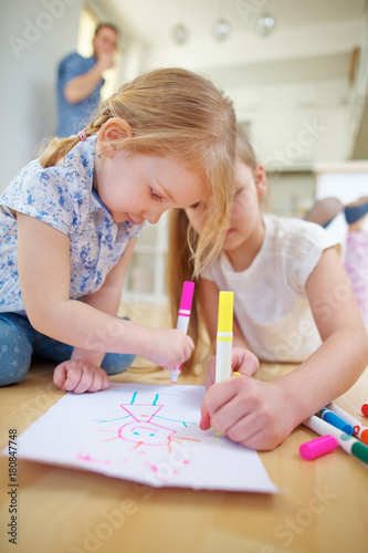 Zwei Kinder malen ein Bild auf Papier