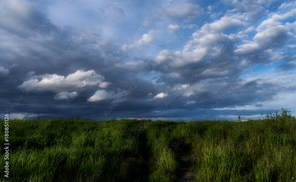 Beautiful dramatic sky with dark clouds over a field with green grass