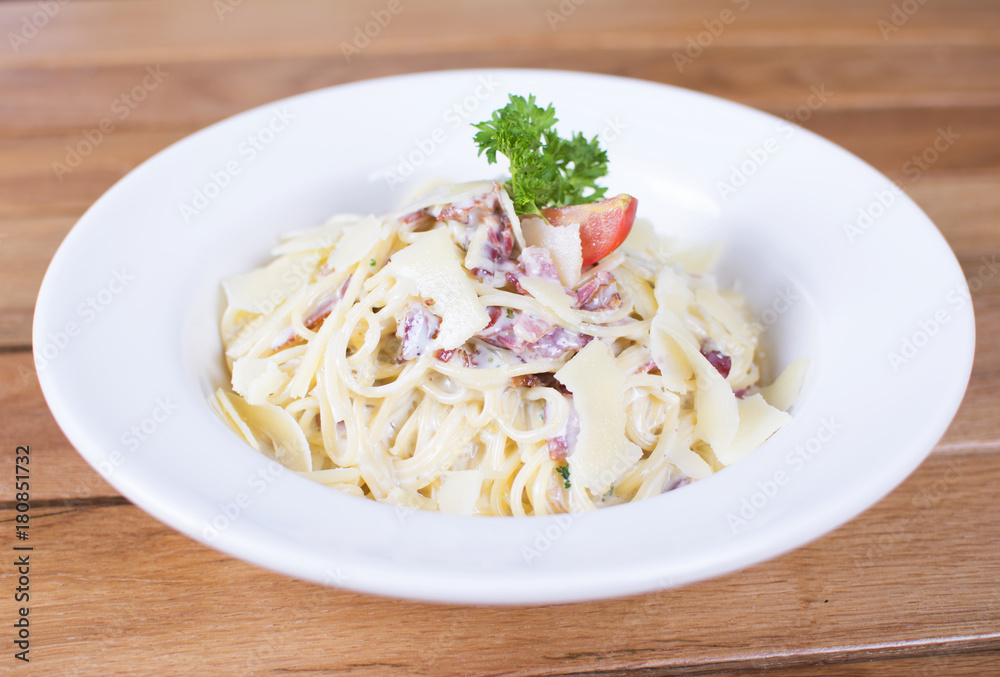 Plate of delicious spaghetti Carbonara with savory minced beef and tomato sauce garnished with parmesan cheese and basil, overhead view.