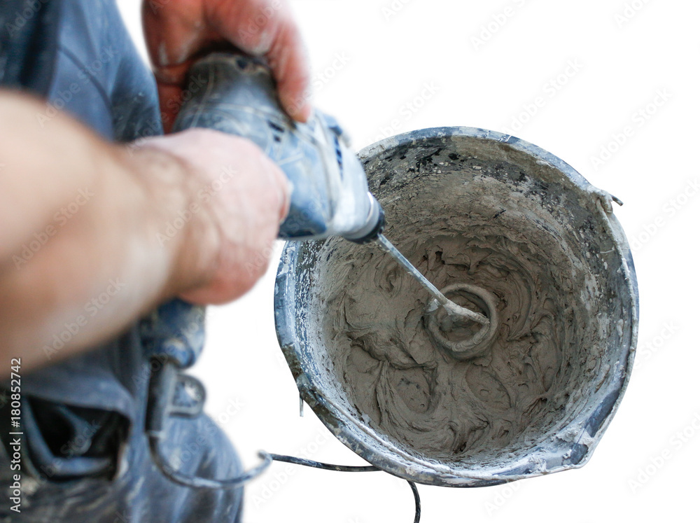 Worker mixing plaster with a drill in a bucket. Isolated on white background.