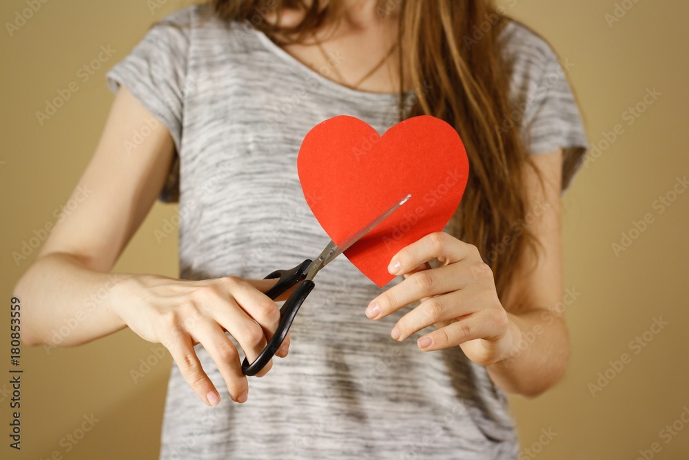 Female hand holding red Valentines card with heart on isolated background. Сut with scissors. Female hand holding red Valentines card with heart on isolated background. Сut with scissors.