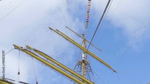 Masts of sail vessel on blue sky background. Rope ladder to the main mast of the ship. photo