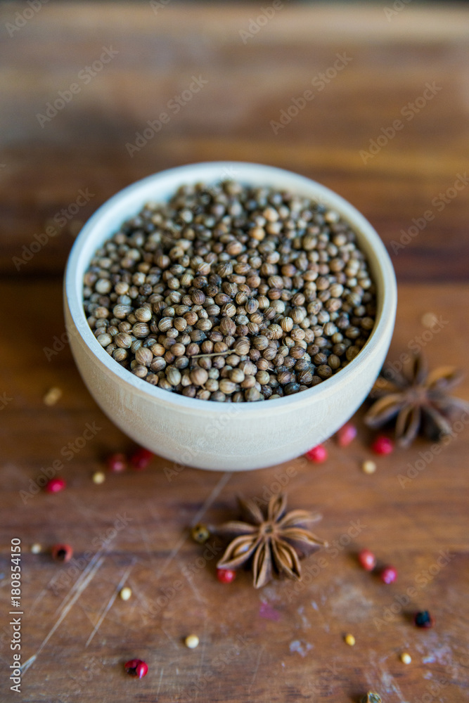 Coriander seeds in bowl on wooden table and spices Coriander seeds in bowl on wooden table and spices