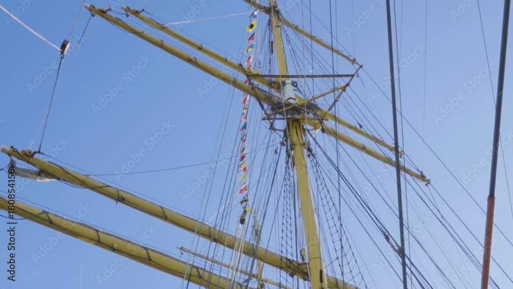 Masts of sail vessel on blue sky background. Rope ladder to the main mast of the ship. Masts of sail vessel on blue sky background. Rope ladder to the main mast of the ship.