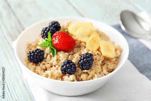 Tasty oatmeal with fruit and berries in bowl on table