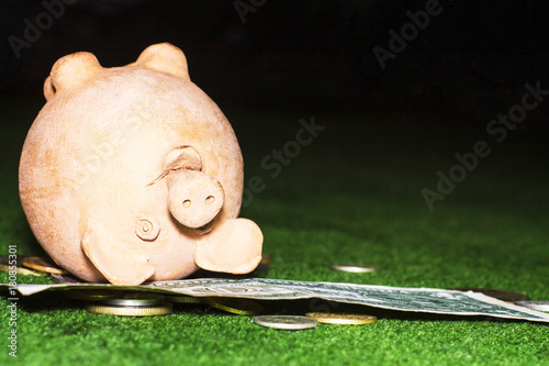 Tax day. Piggy bank with a dollar note and coins against the green carpet background. photo