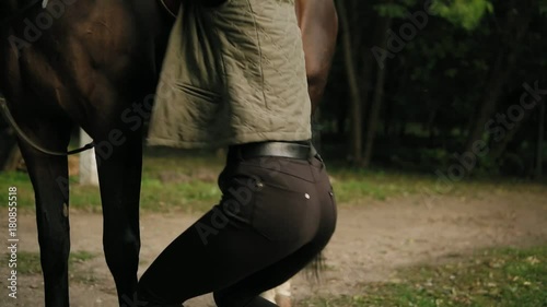 Closeup view of unrecognizable professional horse rider dismounting from the horse, jumping on the ground