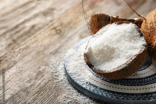 Desiccated coconut in nut on wooden table
