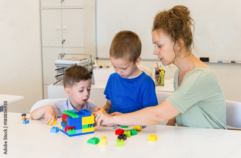 teacher woman play with two child boy with cubes in the kindergarten teacher woman play with two child boy with cubes in the kindergarten