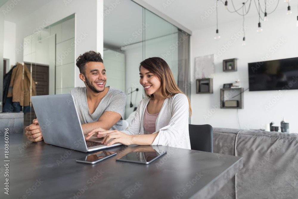 Couple Use Laptop Computer Sitting At Table In Modern Apartment Together Young Man And Woman Surf Internet Happy Smiling Couple Use Laptop Computer Sitting At Table In Modern Apartment Together Young Man And Woman Surf Internet Happy Smiling