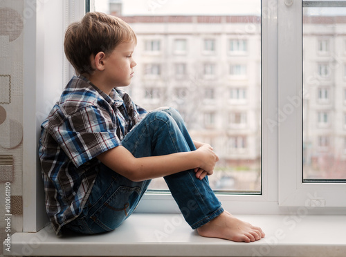 European pensive boy on the windowsill