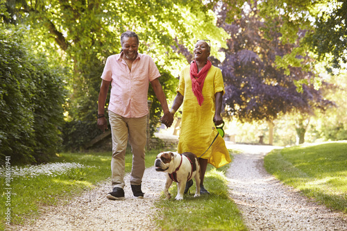 Senior Couple Walking With Pet Bulldog In Countryside photo