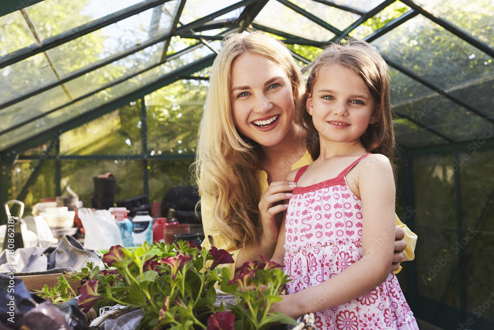 Portrait Of Mother And Daughter Planting Basket In Greenhouse