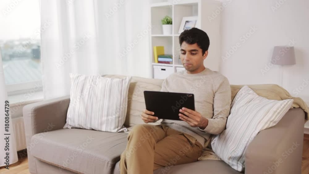 indian man having video call on tablet pc at home indian man having video call on tablet pc at home