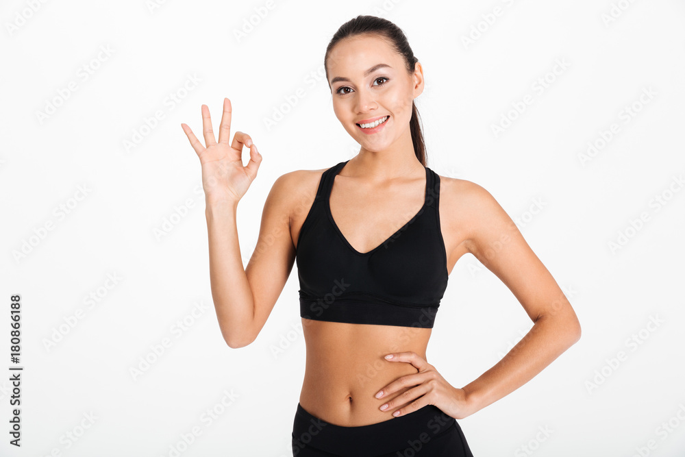 Smiling young sports lady showing okay gesture.