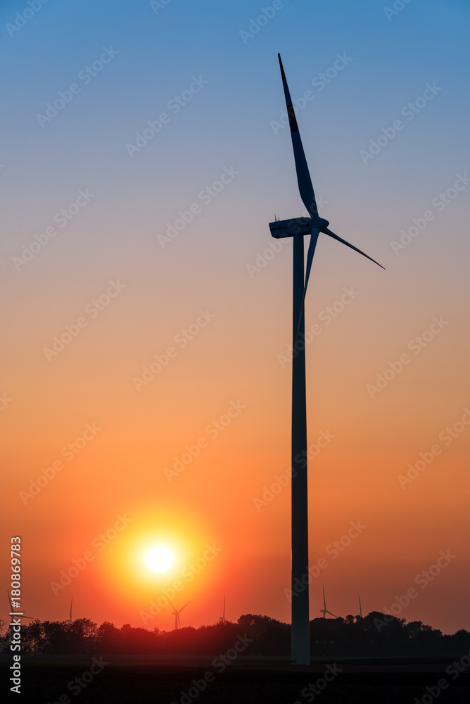 Beautiful landscape with silhouettes of wind turbines at sunset, blue and golden hour. Representing the future of energy production and struggle against climate change. Neurath, NRW, Germany Beautiful landscape with silhouettes of wind turbines at sunset, blue and golden hour. Representing the future of energy production and struggle against climate change. Neurath, NRW, Germany